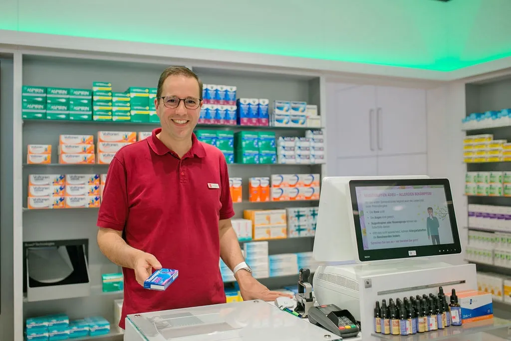 Apotheker Dirk Schuster am HV-Tisch mit Tablettenschachtel in der Hand